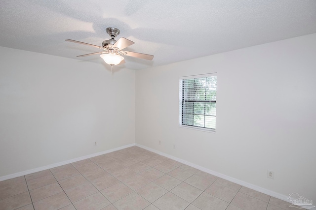 spare room with a textured ceiling, light tile patterned flooring, and ceiling fan