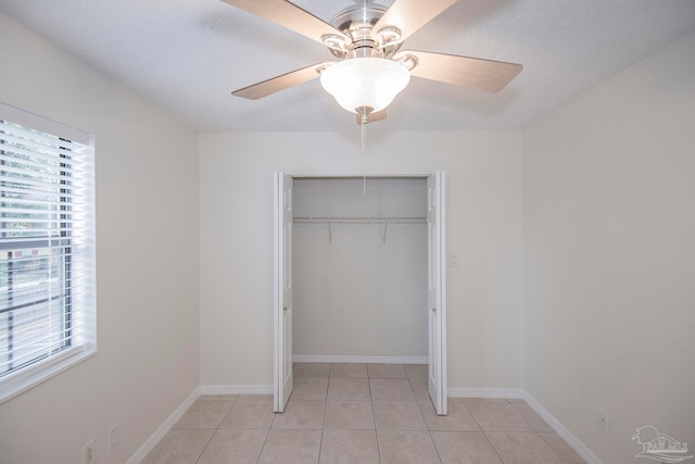 unfurnished bedroom featuring a closet, ceiling fan, light tile patterned floors, and a textured ceiling