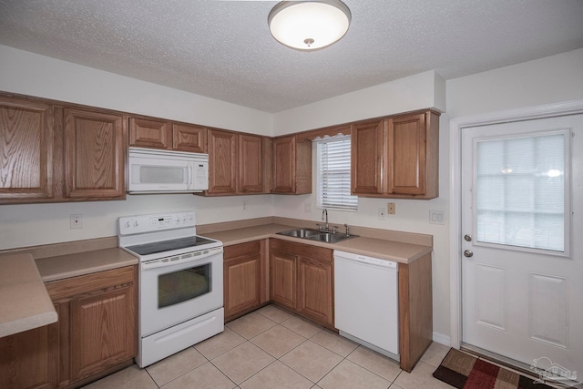 kitchen featuring white appliances, a textured ceiling, light tile patterned flooring, and sink