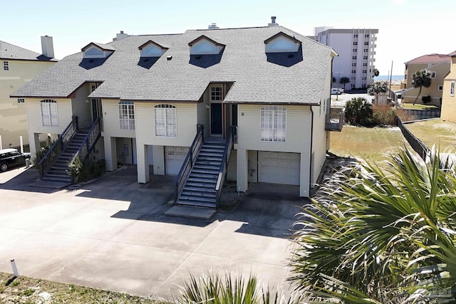 view of front facade featuring a garage, roof with shingles, driveway, and stairway