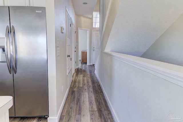 corridor featuring baseboards and dark wood-type flooring