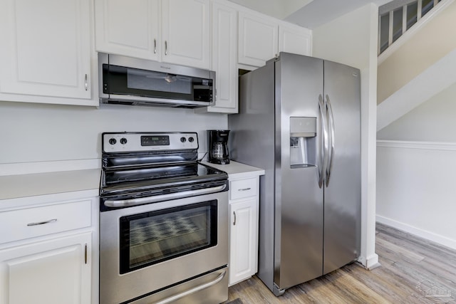 kitchen with light countertops, appliances with stainless steel finishes, light wood-style flooring, and white cabinetry