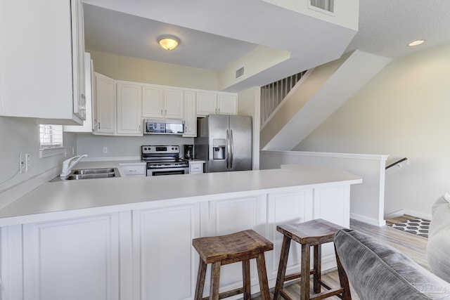 kitchen featuring stainless steel appliances, a peninsula, a sink, visible vents, and light countertops