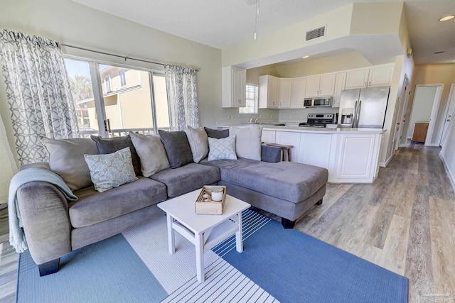 living area featuring light wood-type flooring and visible vents