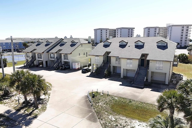 view of front of home with a garage, concrete driveway, stairs, and a residential view