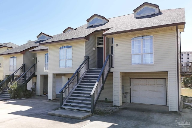 view of front of house with a garage, driveway, stairway, and roof with shingles