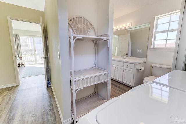 bathroom featuring toilet, vanity, a wealth of natural light, and wood finished floors