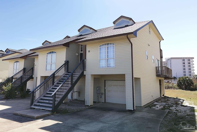 view of front of house with stairs, concrete driveway, roof with shingles, and an attached garage