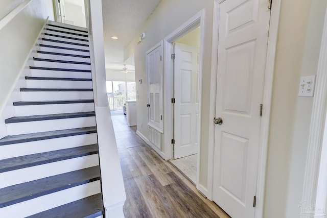 stairs with ceiling fan, wood finished floors, and recessed lighting