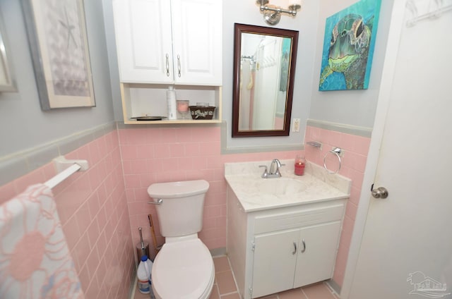 bathroom with tile patterned flooring, vanity, toilet, and tile walls