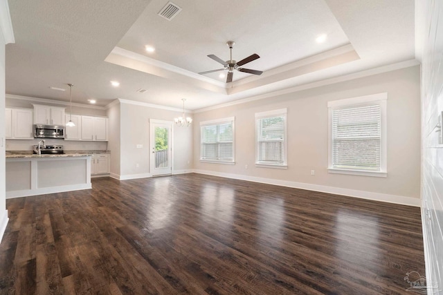 2748 Woodman Loop, Cantonment, FL 32533 - unfurnished living room with a tray ceiling, a ceiling fan, a chandelier, dark wood-type flooring, and crown molding