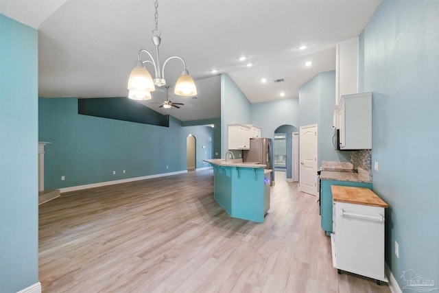 kitchen with light hardwood / wood-style flooring, decorative backsplash, ceiling fan with notable chandelier, white cabinets, and hanging light fixtures