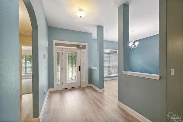 foyer entrance with light wood-type flooring and an inviting chandelier