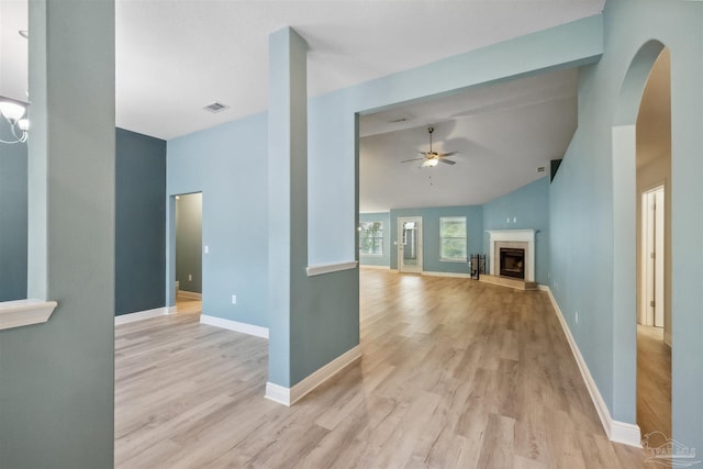 interior space with ceiling fan, a fireplace, vaulted ceiling, and light hardwood / wood-style floors