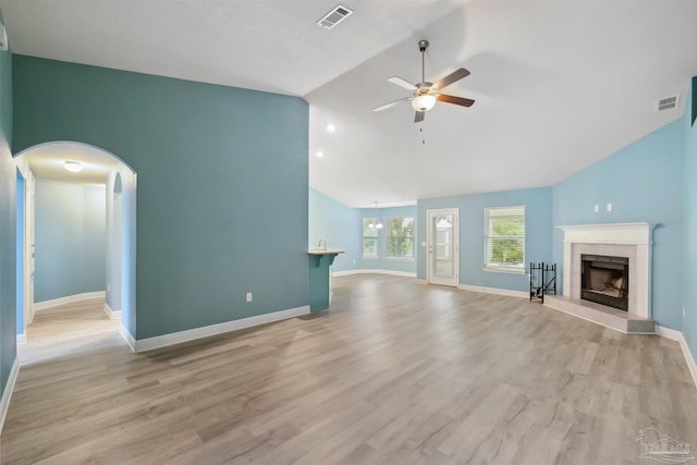 unfurnished living room with ceiling fan, lofted ceiling, light wood-type flooring, and a tile fireplace