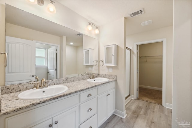 bathroom featuring an enclosed shower, double vanity, and hardwood / wood-style flooring