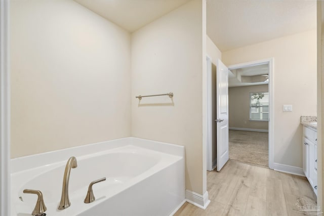 bathroom with a tub, ceiling fan, hardwood / wood-style floors, and vanity