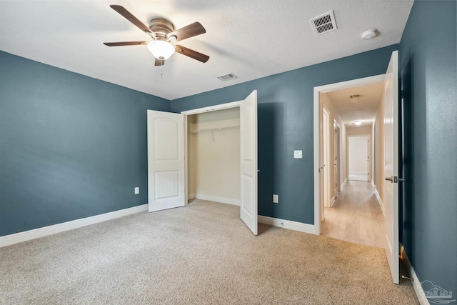 unfurnished bedroom featuring ceiling fan, light colored carpet, and a closet