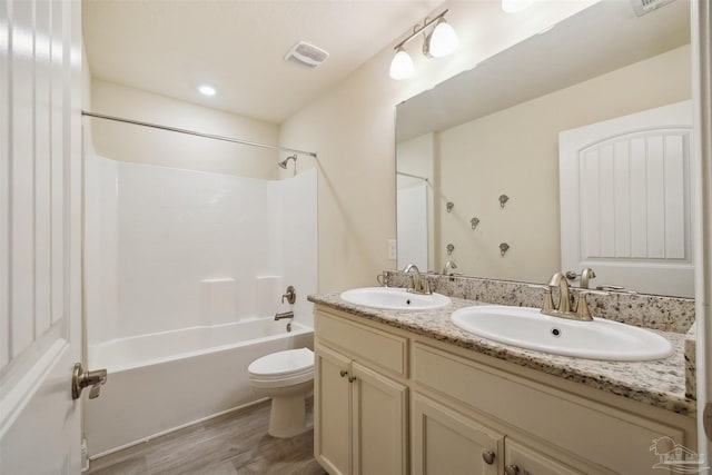 full bathroom featuring wood-type flooring, tub / shower combination, dual vanity, and toilet