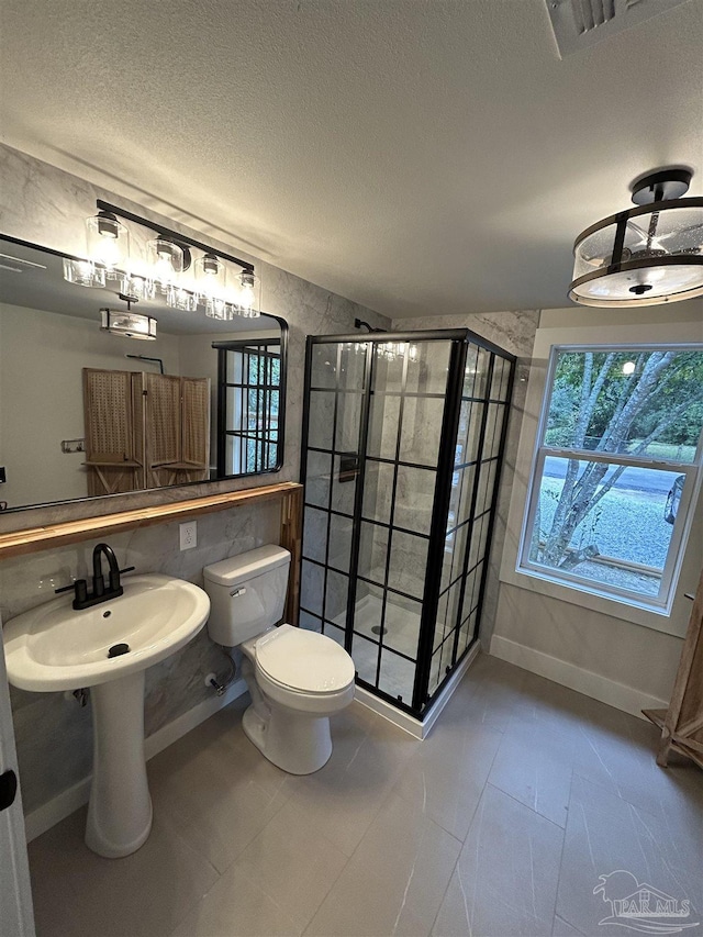 bathroom with tiled shower, toilet, sink, and a textured ceiling