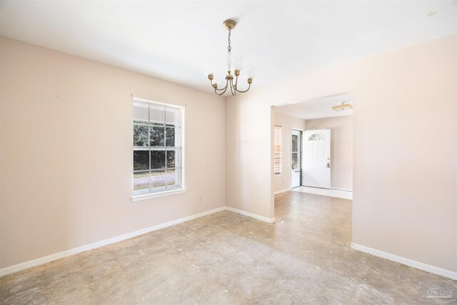 unfurnished room with baseboards, concrete flooring, and a chandelier