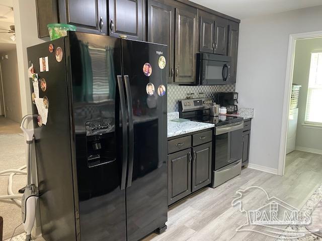 kitchen with decorative backsplash, dark brown cabinets, black appliances, and light stone counters