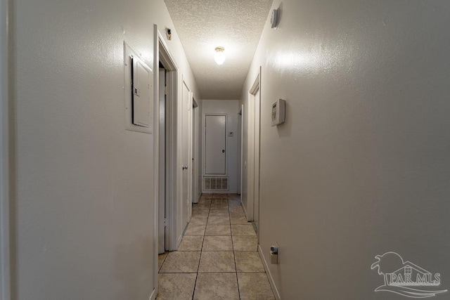 corridor with light tile patterned floors and a textured ceiling