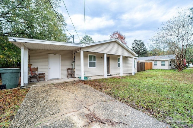 ranch-style home featuring covered porch and a front yard