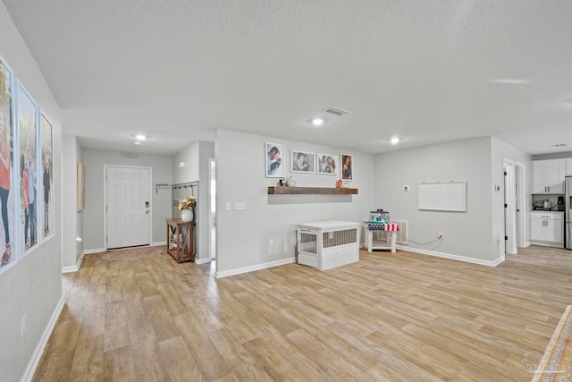 interior space featuring a textured ceiling and light hardwood / wood-style floors