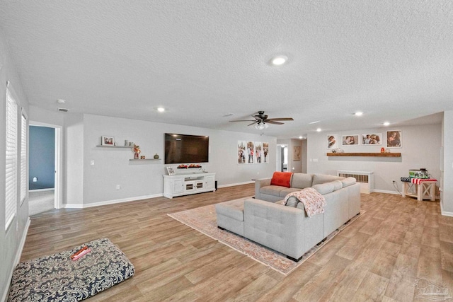 living room featuring ceiling fan, a textured ceiling, and light hardwood / wood-style floors