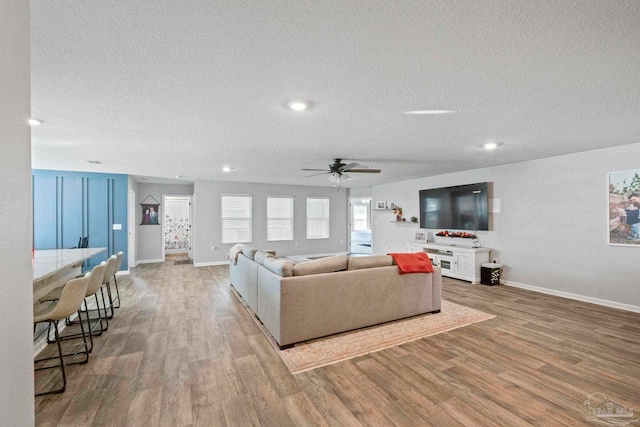 living room with a textured ceiling, hardwood / wood-style flooring, and ceiling fan