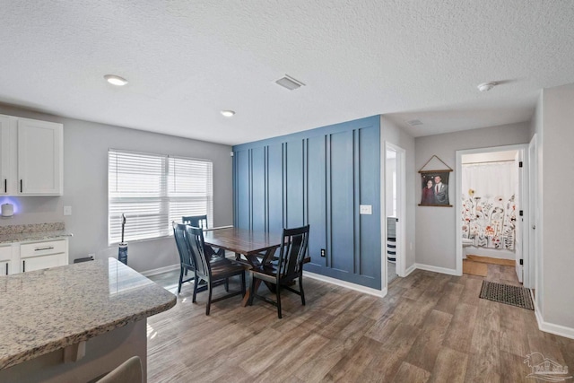 dining area featuring wood-type flooring and a textured ceiling