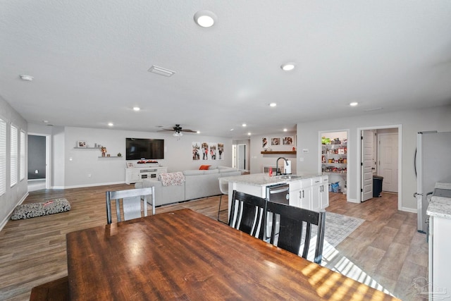 dining area with ceiling fan, sink, and light hardwood / wood-style floors