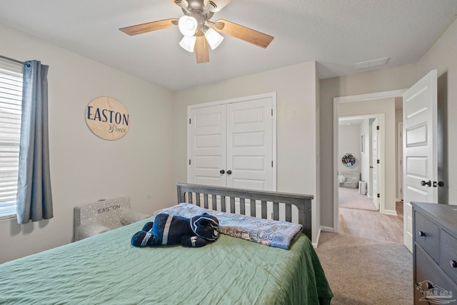 carpeted bedroom with ceiling fan, a textured ceiling, and a closet