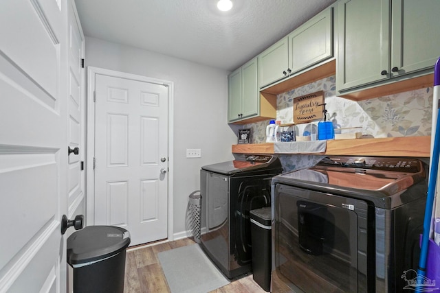 laundry area with cabinets, hardwood / wood-style floors, separate washer and dryer, and a textured ceiling