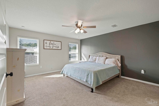 carpeted bedroom featuring multiple windows, a textured ceiling, and ceiling fan