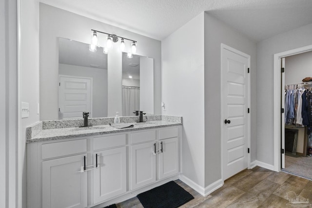 3897 James Stovall St, Pensacola, FL 32526 - full bath featuring wood finished floors, double vanity, a walk in closet, and baseboards