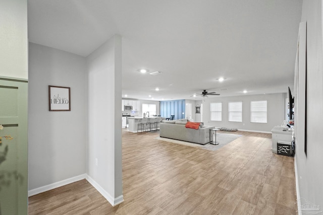 living room with light wood-type flooring and ceiling fan