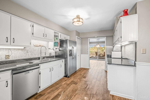 kitchen with sink, wood-type flooring, decorative backsplash, white cabinets, and appliances with stainless steel finishes