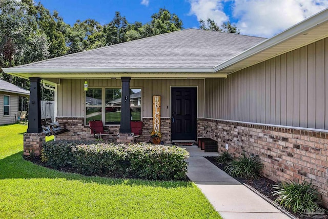 entrance to property featuring a porch and a lawn