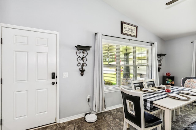 dining room featuring dark tile patterned floors, a healthy amount of sunlight, and vaulted ceiling