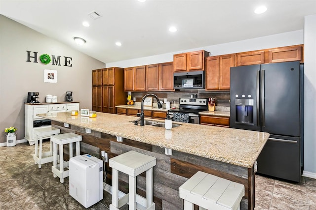 kitchen featuring appliances with stainless steel finishes, sink, decorative backsplash, a kitchen island with sink, and lofted ceiling