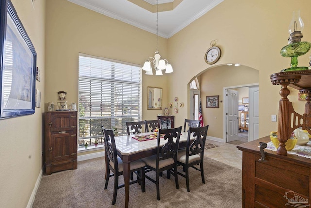 dining room with light carpet, ornamental molding, a chandelier, and a high ceiling