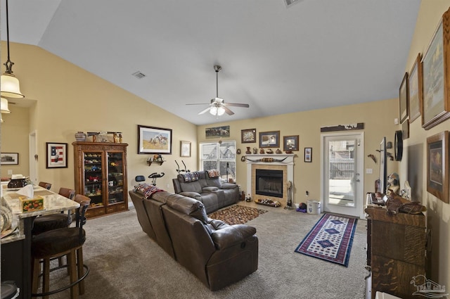 carpeted living room with vaulted ceiling, a tile fireplace, and ceiling fan