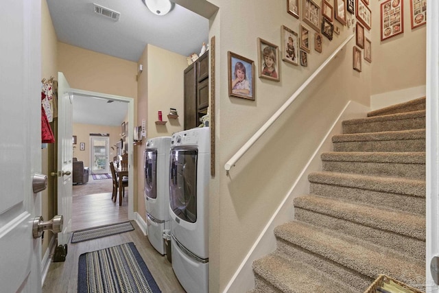 clothes washing area with cabinets, wood-type flooring, and separate washer and dryer