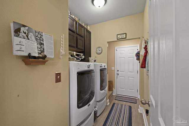 clothes washing area featuring cabinets, separate washer and dryer, and light hardwood / wood-style flooring