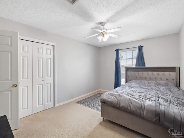 bedroom featuring baseboards, carpet floors, a closet, a textured ceiling, and a ceiling fan