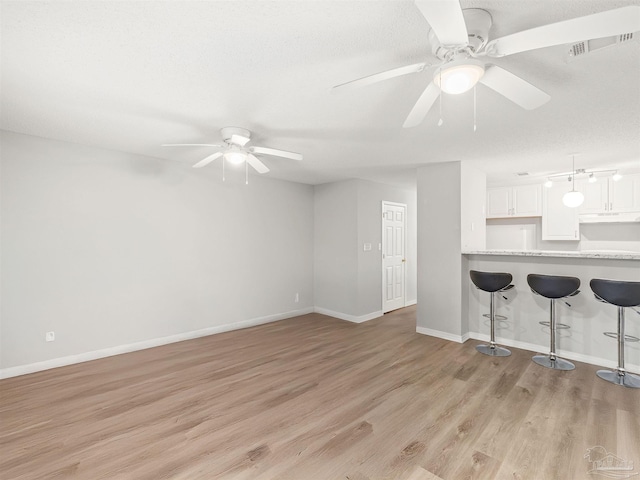 unfurnished living room with visible vents, baseboards, light wood-type flooring, and ceiling fan