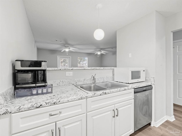 kitchen featuring white microwave, light wood finished floors, ceiling fan, stainless steel dishwasher, and a sink