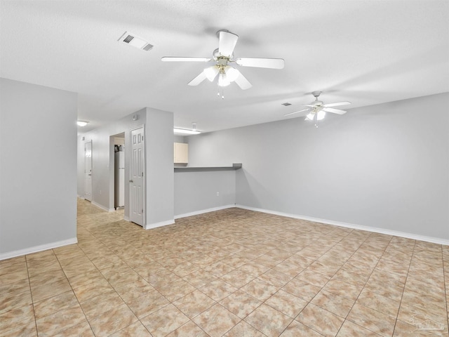 unfurnished living room featuring visible vents, a textured ceiling, baseboards, and a ceiling fan